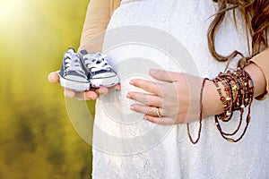 Pregnant woman belly holding baby booties.