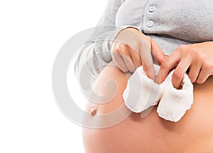 A pregnant woman with a belly holding baby shoes