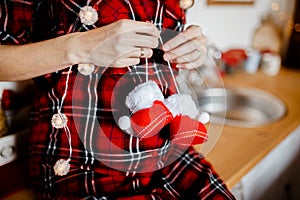 Pregnant woman belly holding red baby booties, expecting girl. Healthy pregnancy. Christmas. Happy New Year