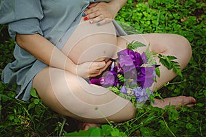 Pregnant Woman Belly. Pregnancy Concept. Over green nature blurred Background. Pregnant tummy close up