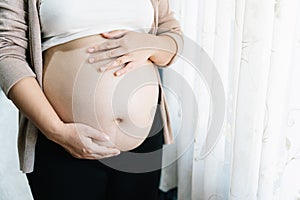 Pregnant woman with big belly at window. pregnancy, motherhood, people and expectation concept. mother