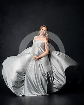 Pregnant woman on black background with big tummy, waiting for baby.