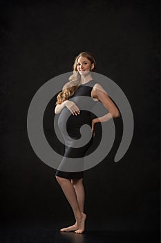 Pregnant woman on black background with big tummy, waiting for baby.