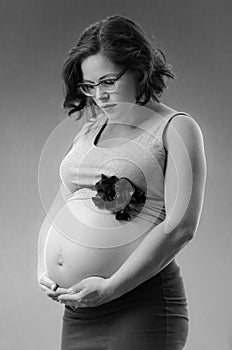 Pregnant woman in black and white background with hands on her b