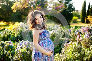 Pregnant woman in the blooming spring garden. Pregnancy and maternity shoot woman. photo