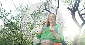 Pregnant woman blowing soap bubbles outdoor