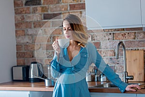 Pregnant woman in blue clothes with cup of tea or coffee