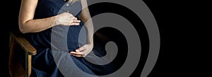 pregnant woman in a blue dress on a dark isolated background banner