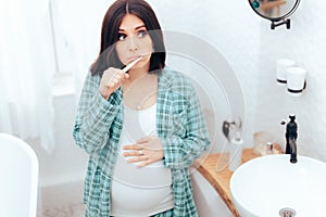 Pregnant Woman Brushing Her Teeth in the Bathroom photo