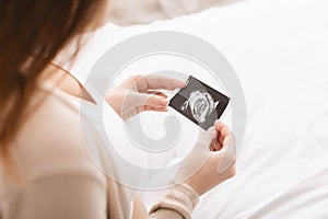 Pregnant woman caressing her belly with sonography
