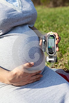 Pregnant woman checking blood sugar level with blood glucometer for prevent gestational diabetes