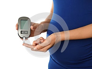 Pregnant woman checking blood sugar level with glucometer on white background. Diabetes test