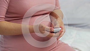 Pregnant woman checking blood sugar level by herself with glucose meter at home. gestational diabetes concept