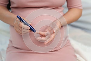 Pregnant woman checking blood sugar level by herself at home. gestational diabetes concept