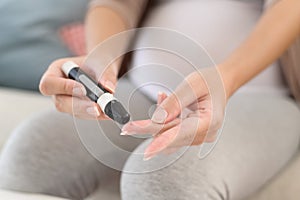 Pregnant woman checking blood sugar level by using Digital Glucose meter, health care, medicine, diabetes, glycemia concept