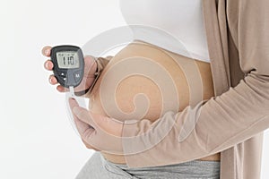 Pregnant woman checking blood sugar level by using Digital Glucose meter, health care, medicine, diabetes, glycemia concept