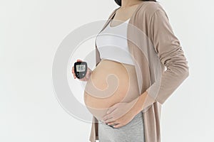 Pregnant woman checking blood sugar level by using Digital Glucose meter, health care, medicine, diabetes, glycemia concept