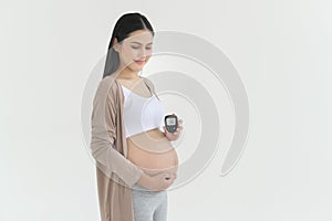 Pregnant woman checking blood sugar level by using Digital Glucose meter, health care, medicine, diabetes, glycemia concept