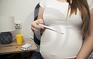pregnant woman is checking the temperature by digital thermometer