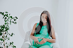 A pregnant woman before childbirth sits in white couch