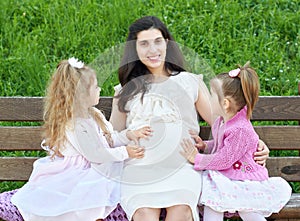 Pregnant woman and children in summer city park outdoor, happy family, bright sunny day and green grass, beautiful people portrait