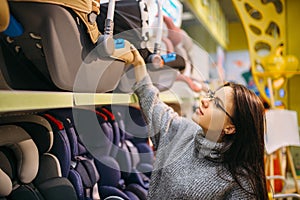 Pregnant woman choosing child car seat in store