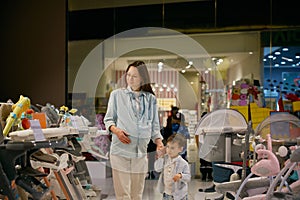 Pregnant woman choosing new chair for baby feeding in shopping mall