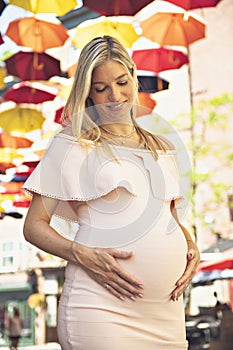 Pregnant woman on city street with umbrella on the background
