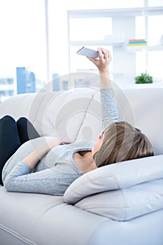 Pregnant woman clicking selfie using smartphone at home