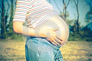 Pregnant woman, with colorful casual clothing, outdoors in the countryside