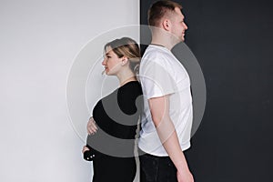 Pregnant woman compare her belly to her husband& x27;s beer belly on black and white background