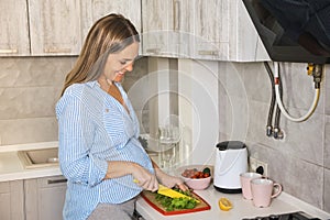 pregnant woman cooking vegetable salad at home kitchen