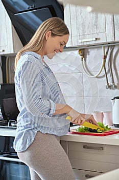 pregnant woman cooking vegetable salad at home kitchen