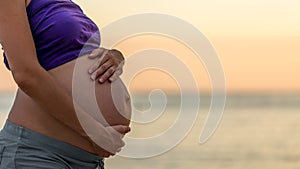 Pregnant woman cradling her belly with her hands photo