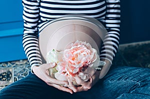 Pregnant woman cuddling belly in bedroom at home just before the labor and childbirth, selective focus