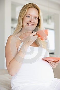 Pregnant woman with cup of tea smiling