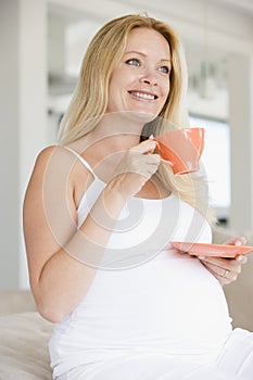 Pregnant woman with cup of tea smiling