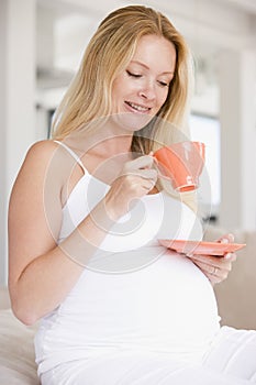 Pregnant woman with cup of tea smiling