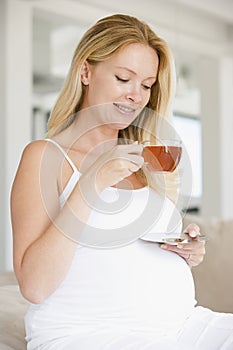 Pregnant woman with cup of tea smiling