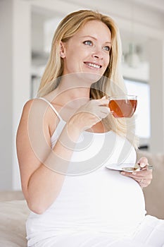 Pregnant woman with cup of tea smiling