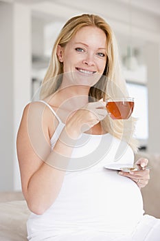 Pregnant woman with cup of tea smiling