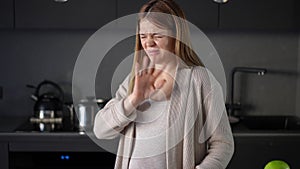 A pregnant woman cuts red beet with a kitchen knife. A woman sniffs a head of garlic and feels intense disgust, covering