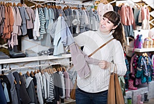 Pregnant woman deciding on clothes for baby in childrenâ€™s clot