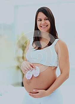 Pregnant woman demonstrates the future baby`s socks.