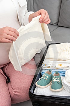 Pregnant woman diligently packing suitcase at home, preparing essentials for maternity hospital, embracing the giving