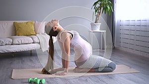 Pregnant woman do exercise for flexibility, flex neck head and lean back, bend on arm. Female