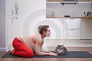 A pregnant woman does yoga at home and does exercises in the cat cow pose