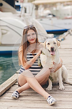 A pregnant woman with a dog on the dock.