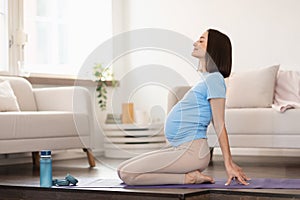 pregnant woman doing backbend during yoga workout at home
