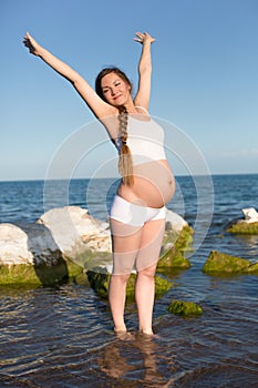 Pregnant woman doing exercise on beach